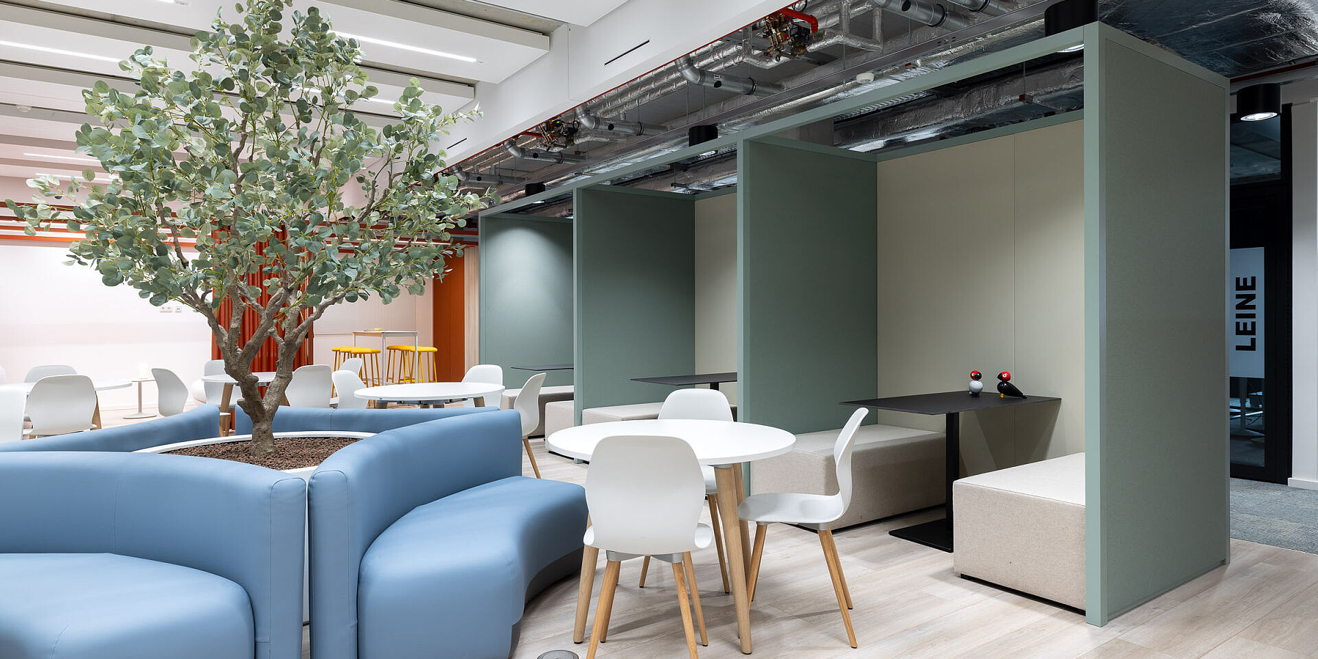 Bistro-Bereich bei Veolia mit weißen se:spot Designstühlen und runden se:assist Tischen, großer Baum in der Mitte, helle, moderne Kantinenumgebung