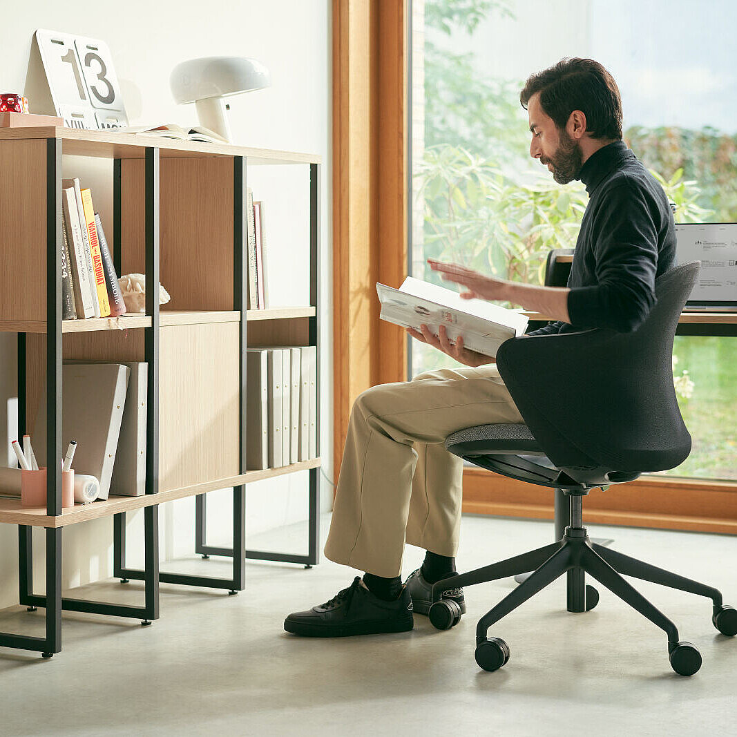 A man sits at a Sedus desk and works